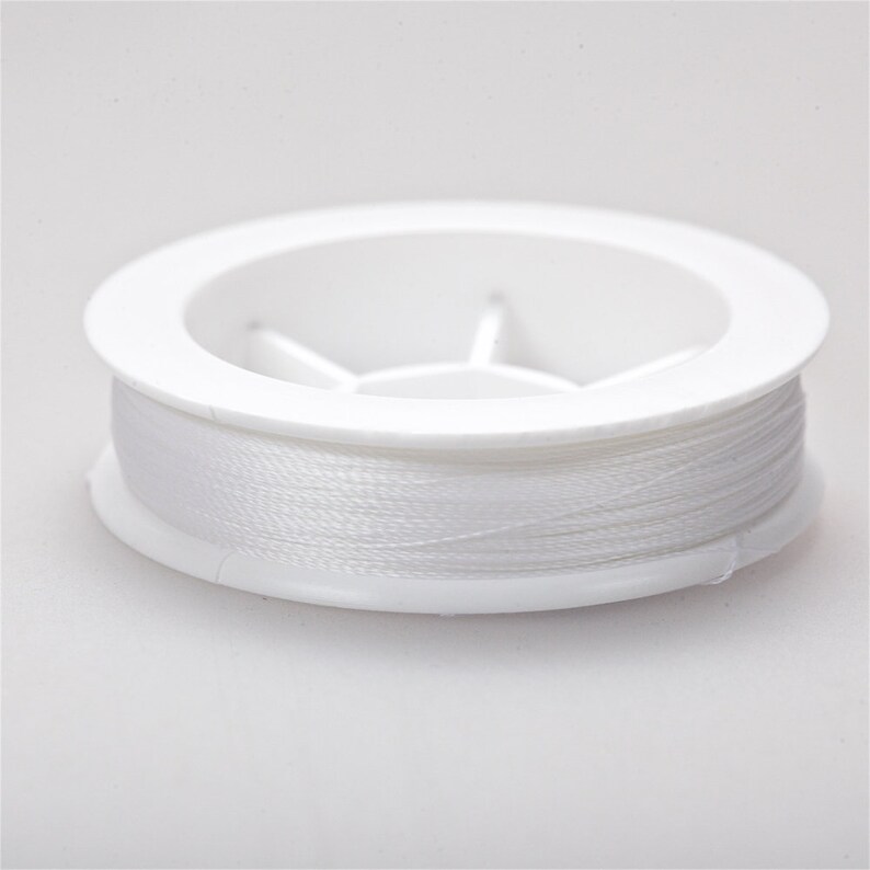 May include: A white spool of thread in a white plastic container.