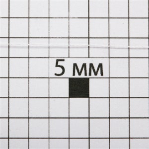 May include: A close-up of a white thread on a gridded surface with a black square and the text "5 MM".