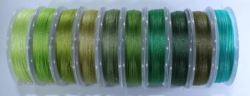 May include: Ten spools of green and blue thread, each wound on a clear plastic spool.