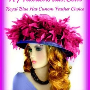 May include: A large, wide-brimmed hat with a royal blue base and a large, fluffy pink feather trim. The hat is worn by a woman with long, curly, auburn hair. The text "NYFashionHats.com Royal Blue Hat Custom Feather Choice" is displayed above the hat.