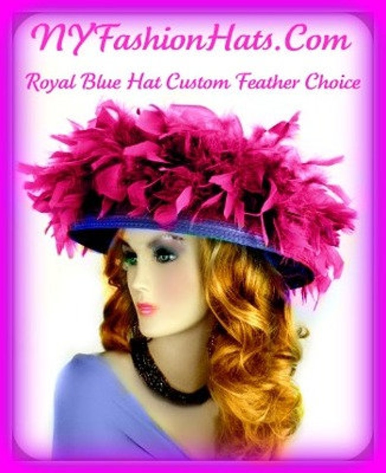 May include: A large, wide-brimmed hat with a royal blue base and a large, fluffy pink feather trim. The hat is worn by a woman with long, curly, auburn hair. The text "NYFashionHats.com Royal Blue Hat Custom Feather Choice" is displayed above the hat.