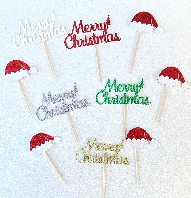May include: Six cupcake toppers with a festive Christmas theme. Each topper features a red, green, silver, or gold glitter "Merry Christmas" message and a small Santa hat.
