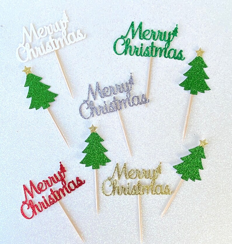 May include: Six cupcake toppers with glitter paper cutouts of Christmas trees and the words "Merry Christmas" in various colors, including white, green, silver, gold, and red.