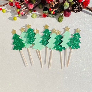 May include: A set of ten green glitter Christmas tree cupcake toppers with gold star accents. The toppers are on white sticks and are perfect for decorating cupcakes or other desserts.