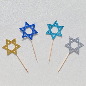 May include: Four glitter star of David cupcake toppers. Two are blue, one is gold, and one is silver.