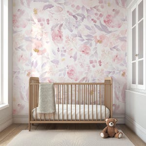 May include: A nursery with a wooden crib, a soft blanket, and a teddy bear on a light-colored rug. The wall is adorned with a floral wallpaper in shades of pink, purple, and white, creating a serene and inviting atmosphere.