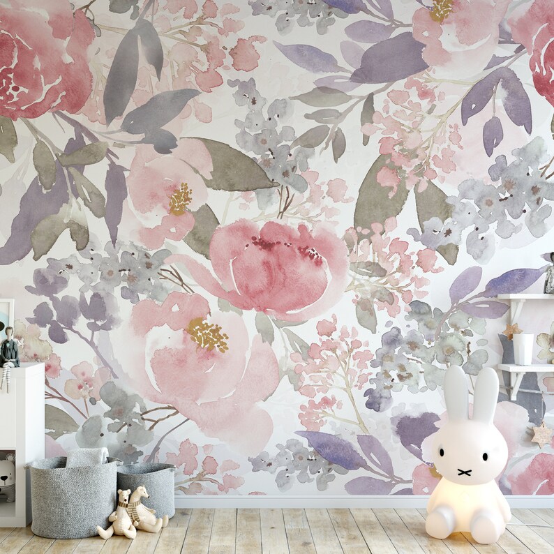 May include: Watercolor floral wallpaper featuring large pink and red roses, lavender and gray leaves, and smaller pink and gray flowers. The design is on a white background. A white bunny lamp and gray storage baskets are in the foreground.