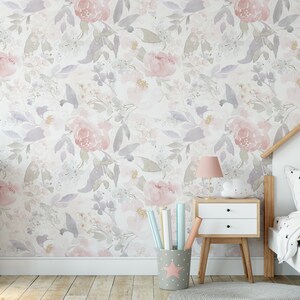 May include: A floral wallpaper featuring watercolor-style pink and purple flowers and leaves. A pink and gray dresser with a heart detail and a white nightstand with a pink lamp are in the room. A bed with a house-shaped headboard is also visible.