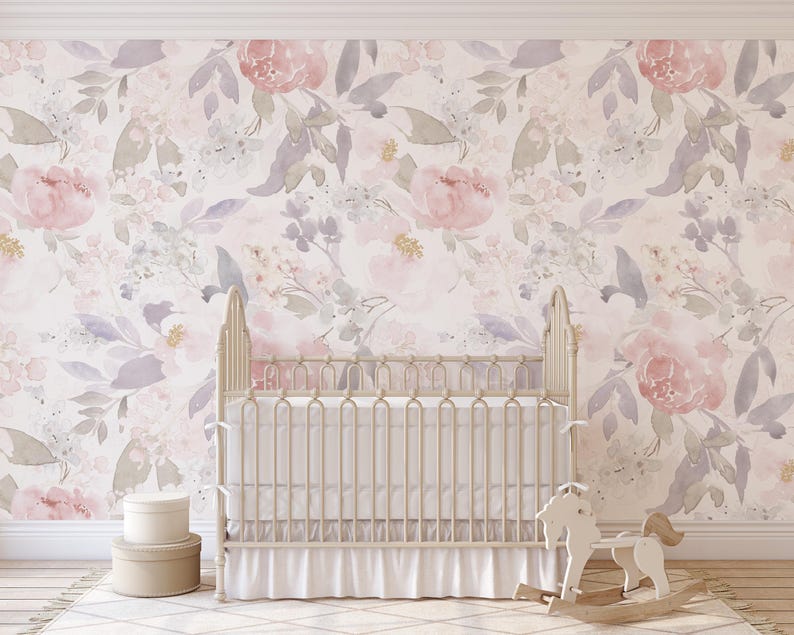 May include: A nursery scene featuring a white crib with a ruffled skirt, set against a floral wallpaper in soft pinks, purples, and greens. A wooden rocking horse and two round boxes complete the decor.