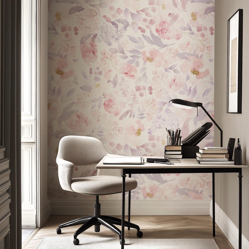 May include: A home office with a floral wallpaper in shades of pink and purple. A beige desk with a black lamp, books, and office supplies sits in front of the wallpaper. A beige chair with black legs is in front of the desk.
