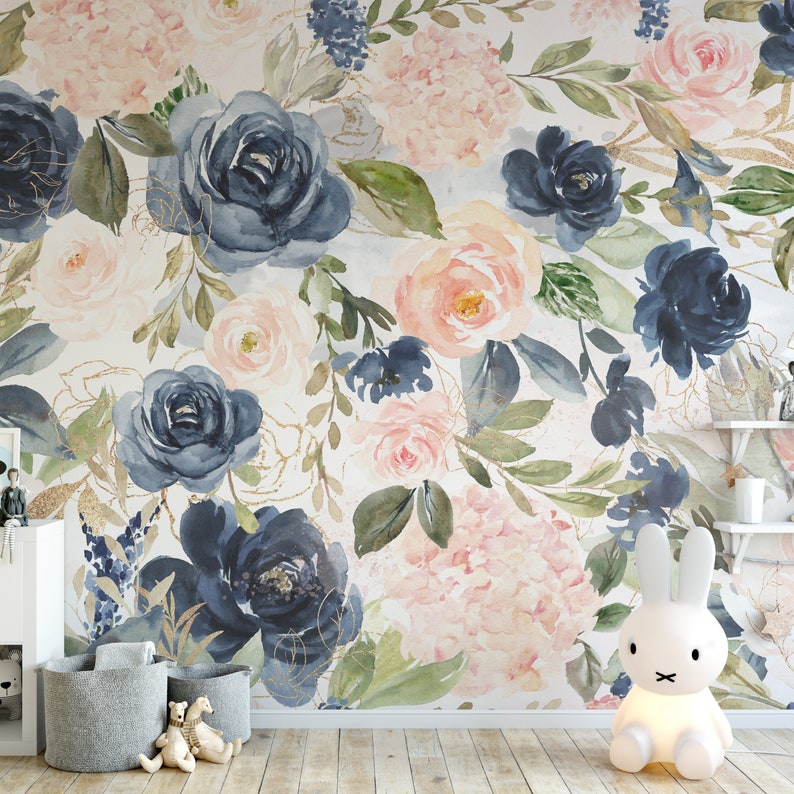 May include: A floral wallpaper featuring watercolor-style roses and hydrangeas in shades of navy blue, blush pink, and cream, with gold accents. The design includes green leaves and is set against a white background. The room also has a white bunny lamp and gray storage baskets.