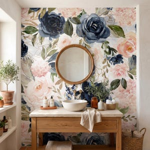 May include: A bathroom vanity with a light wood base and stone top, featuring a white ceramic vessel sink, a round wooden mirror, and floral wallpaper with navy blue and blush pink roses, green leaves, and gold line accents on a white background.