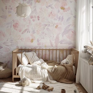 May include: A nursery with a light wood crib, soft bedding, and a floral wallpaper in shades of pink and lavender. A paper lantern hangs from the ceiling. A rug and wooden toys are on the floor.
