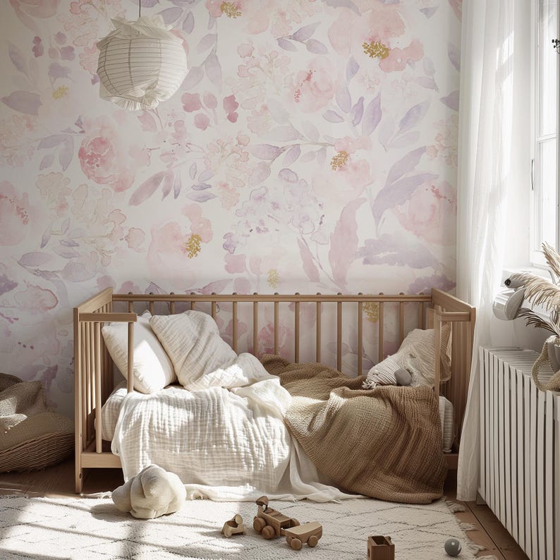 May include: A nursery with a light wood crib, soft bedding, and a floral wallpaper in shades of pink and lavender. A paper lantern hangs from the ceiling. A rug and wooden toys are on the floor.