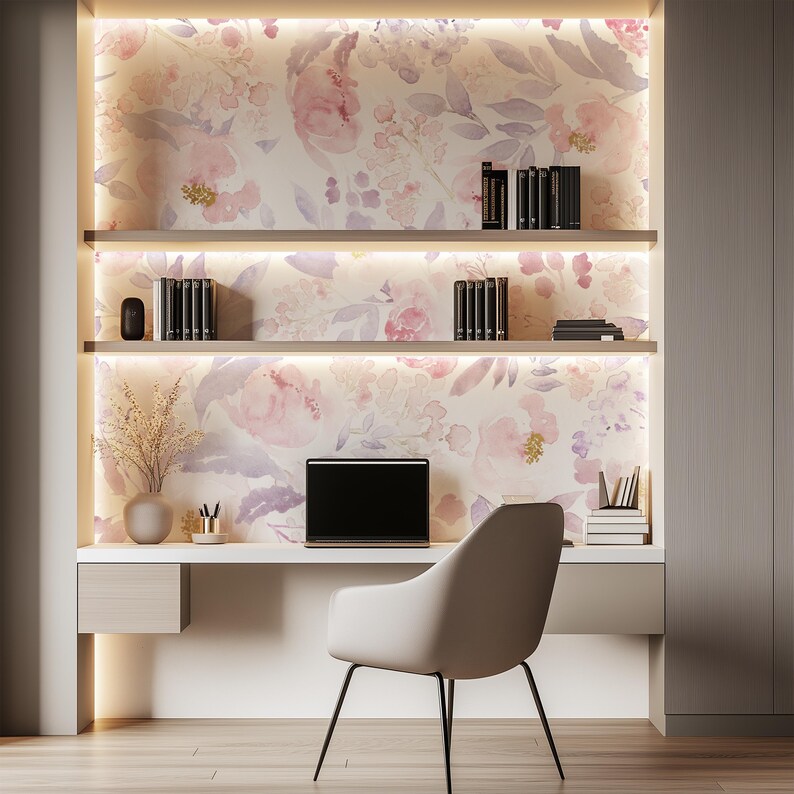 May include: A modern home office setup featuring a built-in desk with shelves and a floral wallpaper backdrop. The desk includes a laptop, a vase with dried flowers, and a minimalist chair. Books and decorative items are arranged on the shelves.