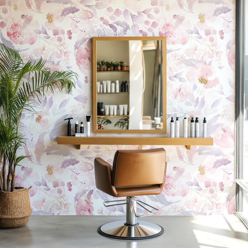 May include: A salon interior featuring a brown leather chair with a chrome base, a wooden-framed mirror, and a wooden shelf with beauty products. The background is a floral wallpaper in shades of pink and purple. A potted plant is in the corner.