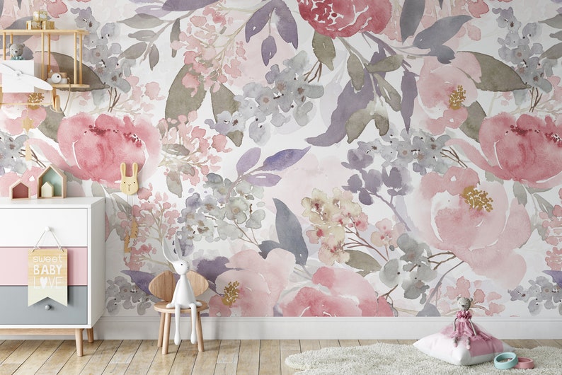 May include: Watercolor floral wallpaper in shades of pink, purple, and gray. The design features large peony blooms and smaller floral clusters. A white dresser, wooden chair, and decorative items are in the foreground.