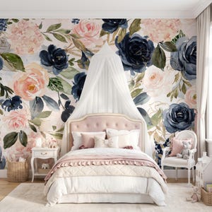 May include: A bedroom featuring a bed with a tufted pink headboard, white bedding, and a white canopy. The wall behind the bed is covered in wallpaper with a large-scale watercolor floral pattern in shades of navy blue, blush pink, and green.