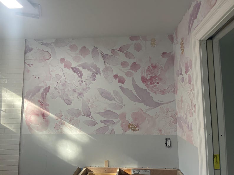 May include: Floral wallpaper featuring a watercolor design of pink and purple flowers and leaves on a white background. The wallpaper covers the wall and extends onto the adjacent wall. The lower portion of the wall is painted a light gray.