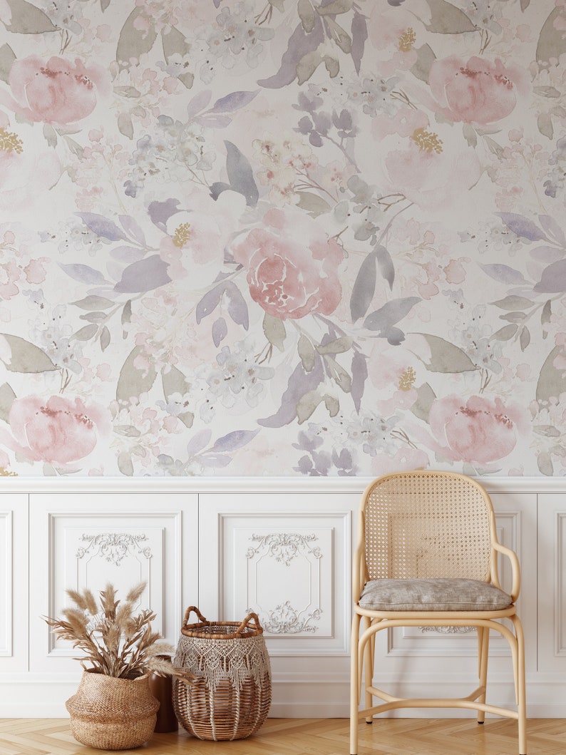 May include: A floral wallpaper featuring watercolor-style pink and purple flowers and green leaves. Below, a white paneled wall with decorative accents, a woven chair, and two woven baskets filled with dried plants.