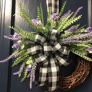 May include: A wreath made of brown twigs with a black and white checkered ribbon bow and purple lavender flowers.