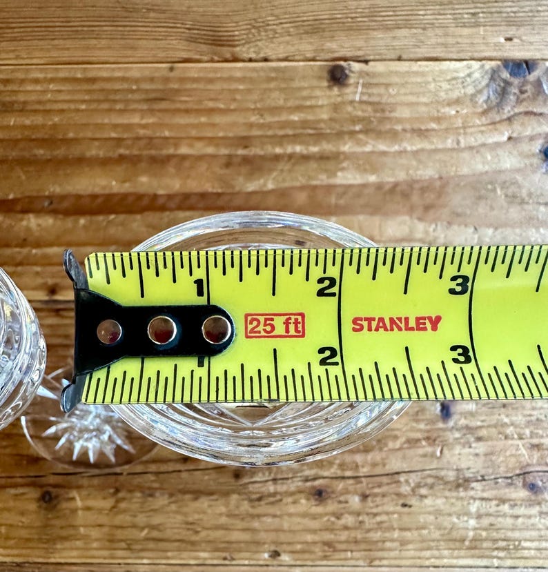May include: A clear glass goblet with a cut crystal design is measured with a yellow tape measure that reads "25 ft" and "STANLEY".