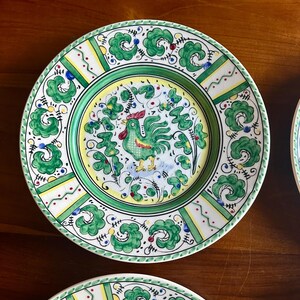 Peut inclure: Assiette en c&eacute;ramique peinte &agrave; la main avec un motif de coq. L'assiette pr&eacute;sente une bordure verte avec des accents blancs et jaunes. Le centre de l'assiette pr&eacute;sente une illustration de coq avec des d&eacute;tails verts et rouges. L'assiette mesure environ 25 cm de diam&egrave;tre.