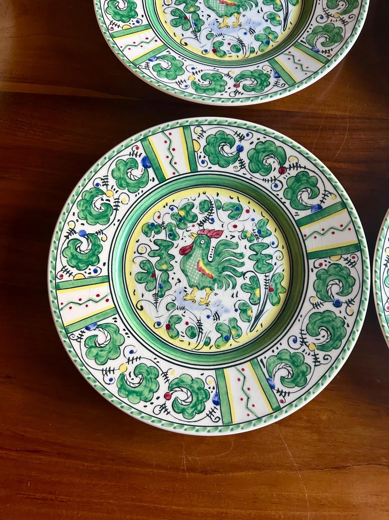 Peut inclure: Ensemble d'assiettes d&eacute;coratives en c&eacute;ramique avec un motif de coq. Les assiettes pr&eacute;sentent une palette de couleurs verte, jaune et blanche avec des motifs floraux et g&eacute;om&eacute;triques complexes. Le coq est au centre de l'assiette.