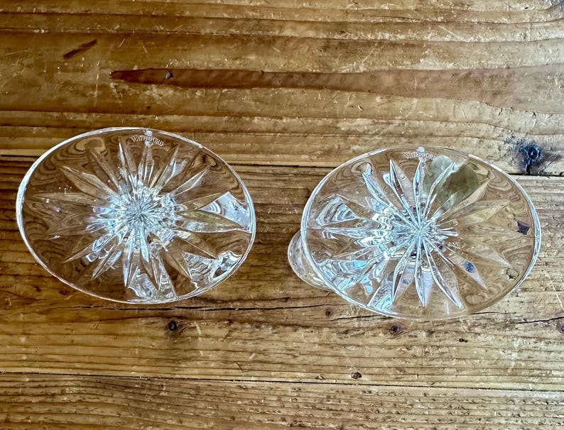May include: Two clear glass candle holders with a starburst pattern. The holders are empty and have a smooth, polished finish.