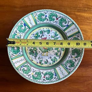 Peut inclure: Une assiette d&eacute;corative en c&eacute;ramique avec un motif de coq. L'assiette pr&eacute;sente une bordure verte et blanche avec un centre jaune. L'assiette mesure environ 30 cm de diam&egrave;tre.