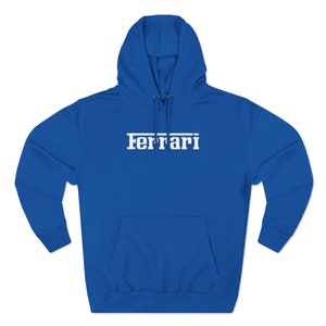 May include: A royal blue hoodie with a white "Ferrari" logo across the chest. The hoodie features a drawstring hood and a front kangaroo pocket. The long-sleeved sweatshirt is made of a soft material.