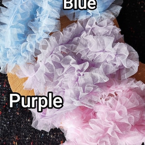 Pu&ograve; includere: Tre strisce di tessuto in tulle arricciato in azzurro, viola chiaro e rosa chiaro. Ogni striscia presenta una consistenza densa e increspata. Il testo Blue, Purple e Pink &egrave; stampato sull'immagine per identificare ogni colore del tulle.