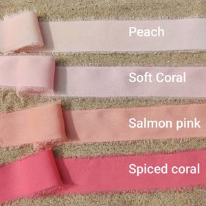 Puede incluir: Cuatro tiras de cinta de tela con bordes deshilachados dispuestas horizontalmente. Los colores est&aacute;n etiquetados como Peach, Soft Coral, Salmon pink y Spiced coral. Cada cinta presenta una textura suave y un borde crudo y sin rematar.
