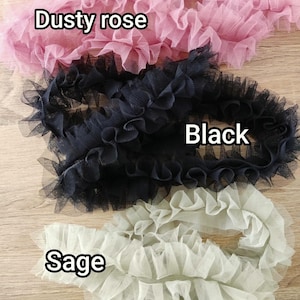 Pu&ograve; includere: Tre strisce di nastro in tulle arricciato disposte in file orizzontali. Il nastro superiore &egrave; rosa polvere, quello centrale &egrave; nero e quello inferiore &egrave; color salvia. Ogni pezzo presenta una consistenza pieghettata in tessuto a rete fine.