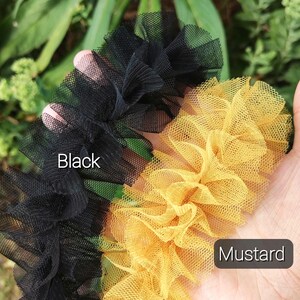 Pu&ograve; includere: Due strisce di tessuto in tulle arricciato, una nera e una giallo senape. La striscia nera &egrave; etichettata con il testo Black e la striscia giallo senape con il testo Mustard. Il tessuto presenta una trama a rete fine e aperta.