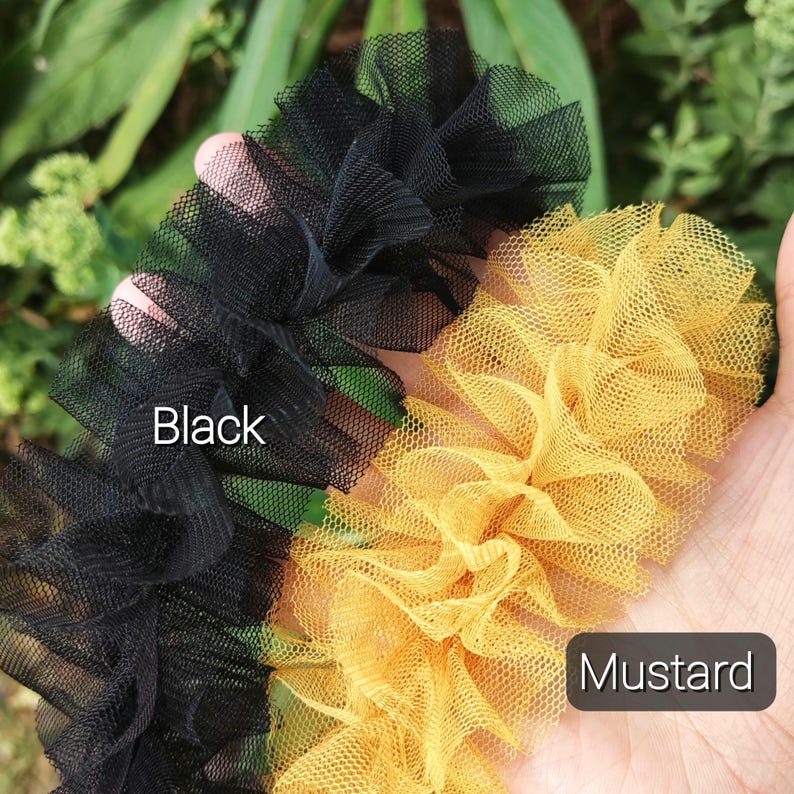 Pu&ograve; includere: Due strisce di tessuto in tulle arricciato, una nera e una giallo senape. La striscia nera &egrave; etichettata con il testo Black e la striscia giallo senape con il testo Mustard. Il tessuto presenta una trama a rete fine e aperta.