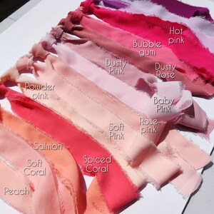 Puede incluir: Una colecci&oacute;n de cintas de tela con bordes deshilachados dispuestas en un degradado de tonos rosa y coral. Las cintas est&aacute;n etiquetadas con texto que incluye Hot pink, Bubble gum, Dusty Pink, Dusty Rose, Powder pink, Baby Pink, Soft Pink, Rose pink, Salmon, Spiced Coral, Soft Coral y Peach.