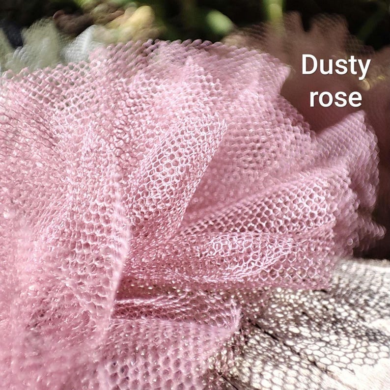 Pu&ograve; includere: Un tessuto in tulle color rosa antico con un fine motivo a rete esagonale. Il materiale &egrave; raccolto in pieghe morbide e voluminose, creando un aspetto stratificato e strutturato. Il testo "Dusty rose" &egrave; stampato in bianco in alto a destra.