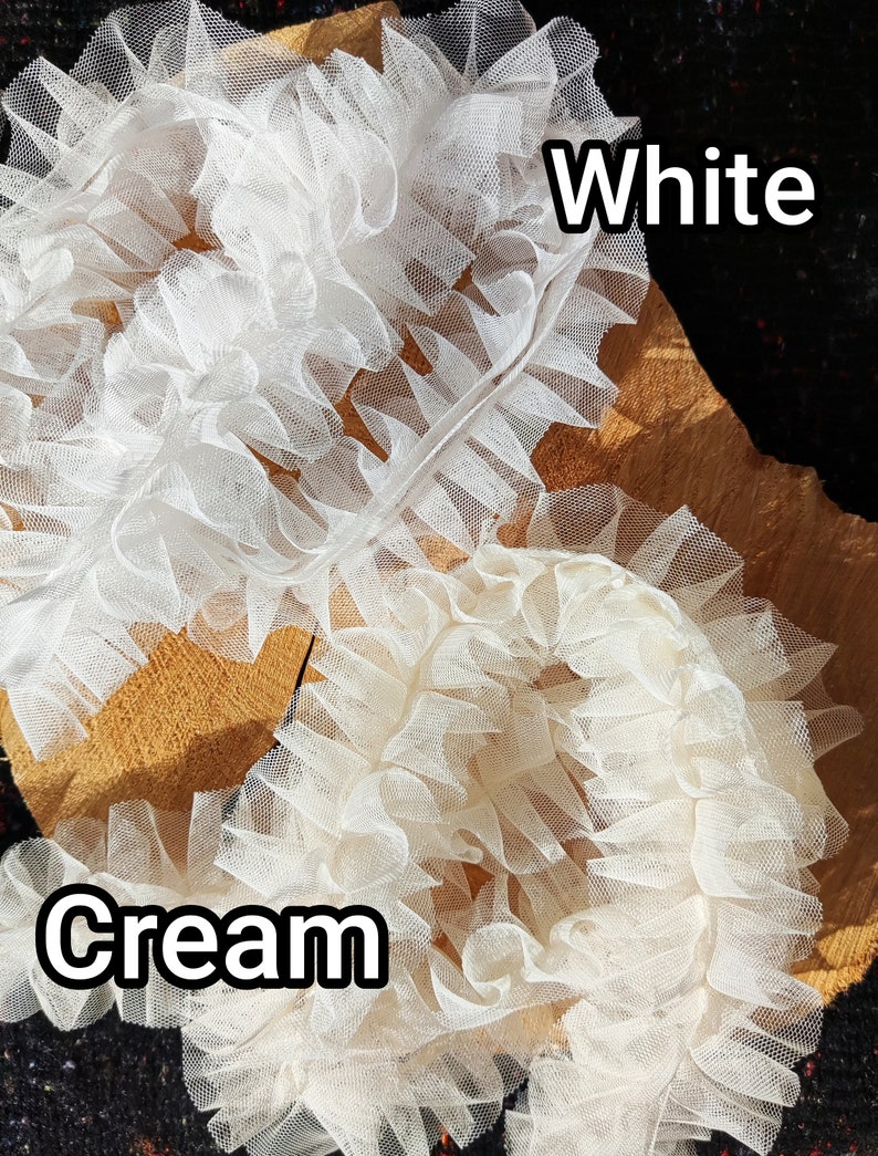 Pu&ograve; includere: Due rotoli di nastro in tulle arricciato, uno bianco e uno color crema. Il tessuto in rete fine e trasparente &egrave; raccolto in fitte pieghe ondulate lungo un bordo centrale. Il testo White &egrave; posizionato vicino al rotolo superiore, Cream a quello inferiore.
