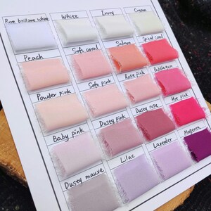 Puede incluir: Una carta de colores con veinte muestras de tela dispuestas en una cuadr&iacute;cula sobre una hoja blanca. Cada muestra est&aacute; etiquetada con texto escrito a mano que incluye Pure brilliant white, White, Ivory, Cream, Peach, Soft coral, Salmon, Spiced coral, Powder pink, Soft pink, Rose pink, Bubblegum, Baby pink, Dusty pink, Dusty rose, Hot pink, Dusty mauve, Lilac, Lavender y Magenta.
