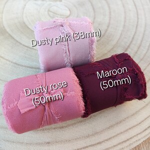 Puede incluir: Tres rollos de cinta con bordes deshilachados en rosa polvoriento, rosa viejo y granate. La cinta rosa polvoriento mide 38 mm de ancho, mientras que las cintas rosa viejo y granate miden 50 mm de ancho cada una. Cada rollo lleva un lazo fino.