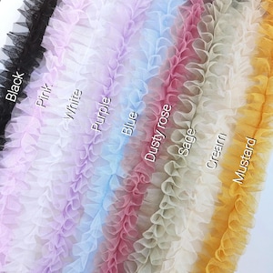 Pu&ograve; includere: Una collezione di strisce di bordo in tulle arricciato disposte verticalmente in vari colori, tra cui nero, rosa, bianco, viola, blu, rosa antico, salvia, crema e senape. Ogni striscia &egrave; etichettata con il nome del colore in bianco.