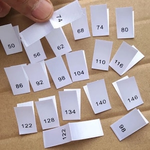 Storleksetiketter i satin för barn- och babykläder, som anger månad eller tysk klädstorlek, för isyning.