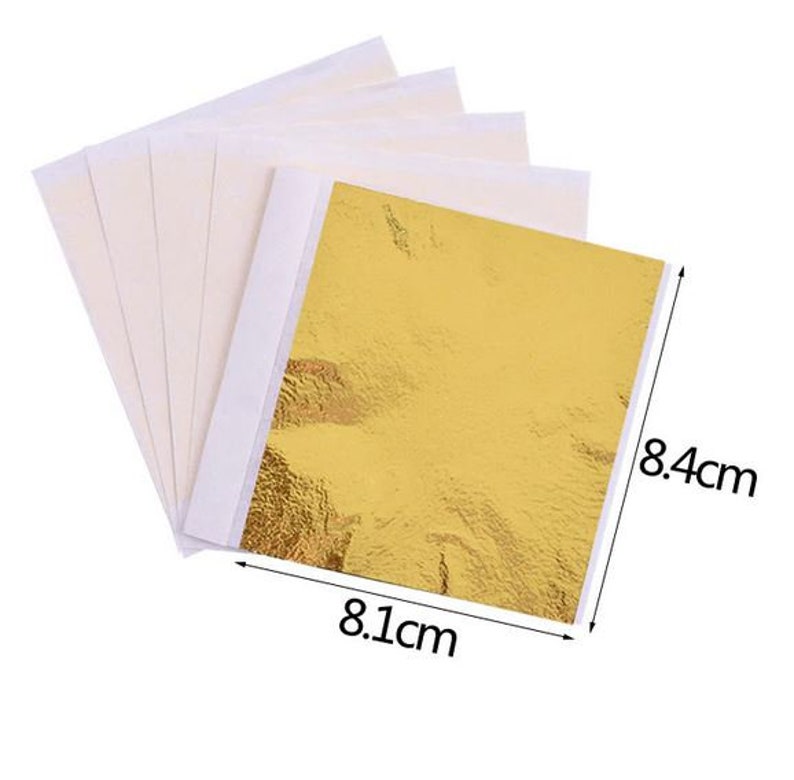 Pu&ograve; includere: Un foglio di foglia d'oro che misura 8,1 cm per 8,4 cm. La foglia d'oro &egrave; su un foglio di supporto bianco.