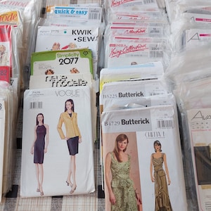 Könnte beinhalten: Eine Sammlung von Vintage-Schnittmustern für Kleidung. Die Muster sind in verschiedenen Farben und zeigen verschiedene Designs, darunter Kleider, Jacken und Röcke. Die Muster sind mit verschiedenen Marken gekennzeichnet, darunter Simplicity, Vogue, Butterick und Kwik Sew.