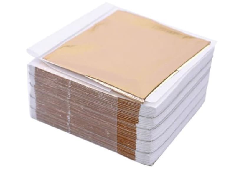 Pu&ograve; includere: Un pacco di fogli di oro in un involucro di plastica trasparente. I fogli sono impilati uno sopra l'altro e sono pronti per essere utilizzati per lavori di artigianato o progetti artistici.