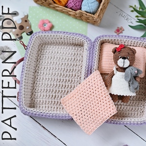 Può includere: Valigia all'uncinetto in lavanda e beige, contenente un orsacchiotto con un vestito bianco e un coniglietto grigio. All'interno un cuscino e una coperta rosa chiaro. Il testo "PATTERN PDF" è visibile sul lato sinistro.