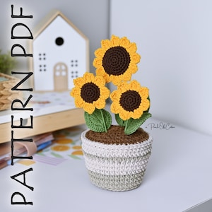 May include: A crocheted sunflower arrangement in a striped pot. The sunflowers have yellow petals and brown centers, with green leaves. The pot is white and gray. The text "PATTERN PDF" is on the left side of the image.