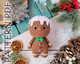 May include: A crocheted gingerbread man toy with white icing, colorful sprinkles, and brown buttons. The toy is wearing a green bow tie and is standing on a white surface.