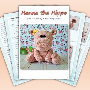 May include: A crochet pattern titled "Hanna the Hippo" by A Pinch of Cotton. The pattern features a plush, pink hippo with a yellow flower on its head. The image includes pattern pages with instructions and a finished hippo toy.